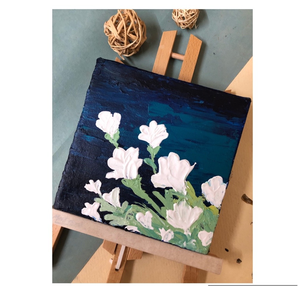 Acrylic painting of white flowers with thick impasto petals against a dark navy-to-teal background, displayed on a mini easel