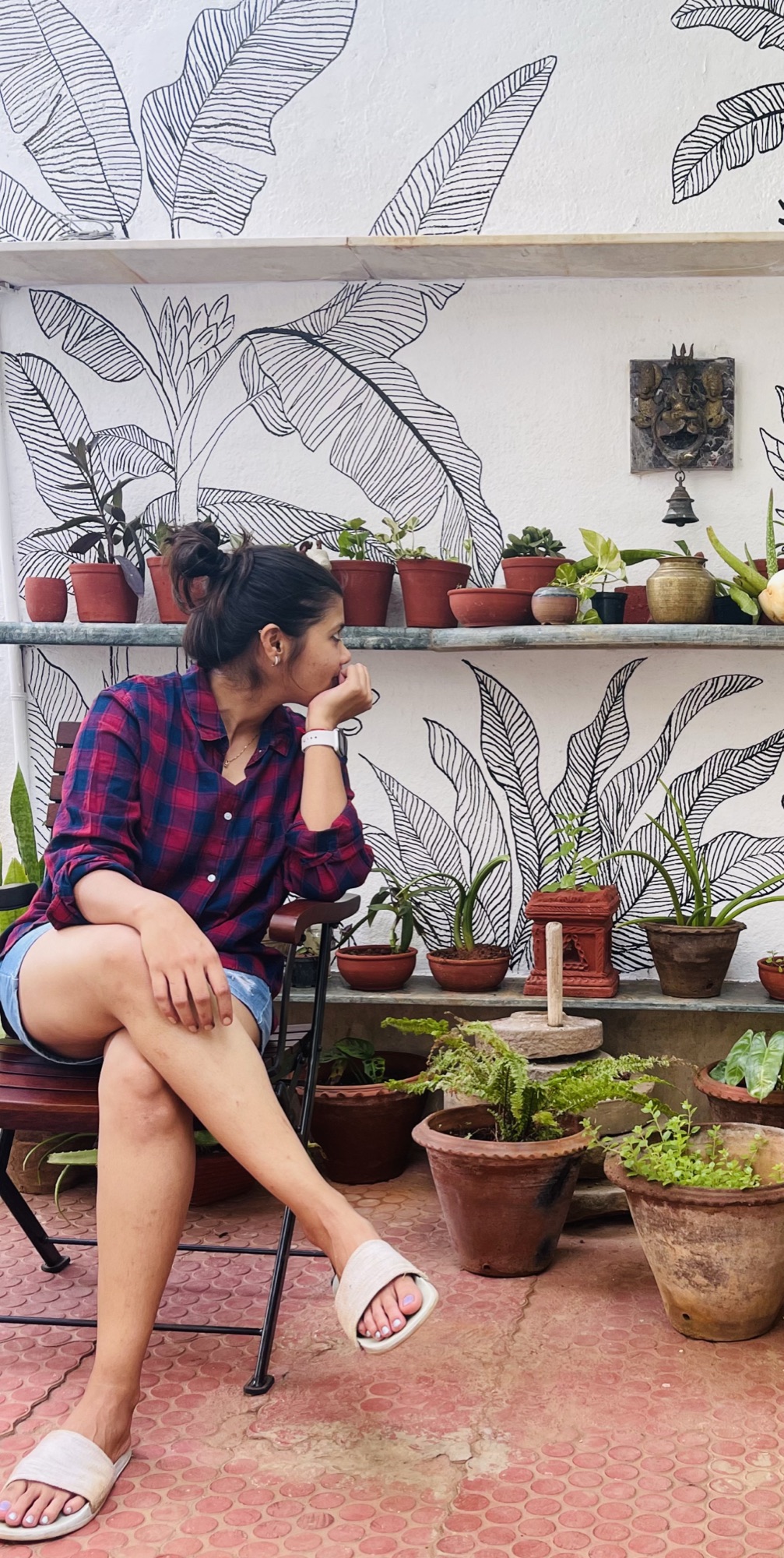 Shilpa Kankaria sitting in front of her hand-painted botanical mural